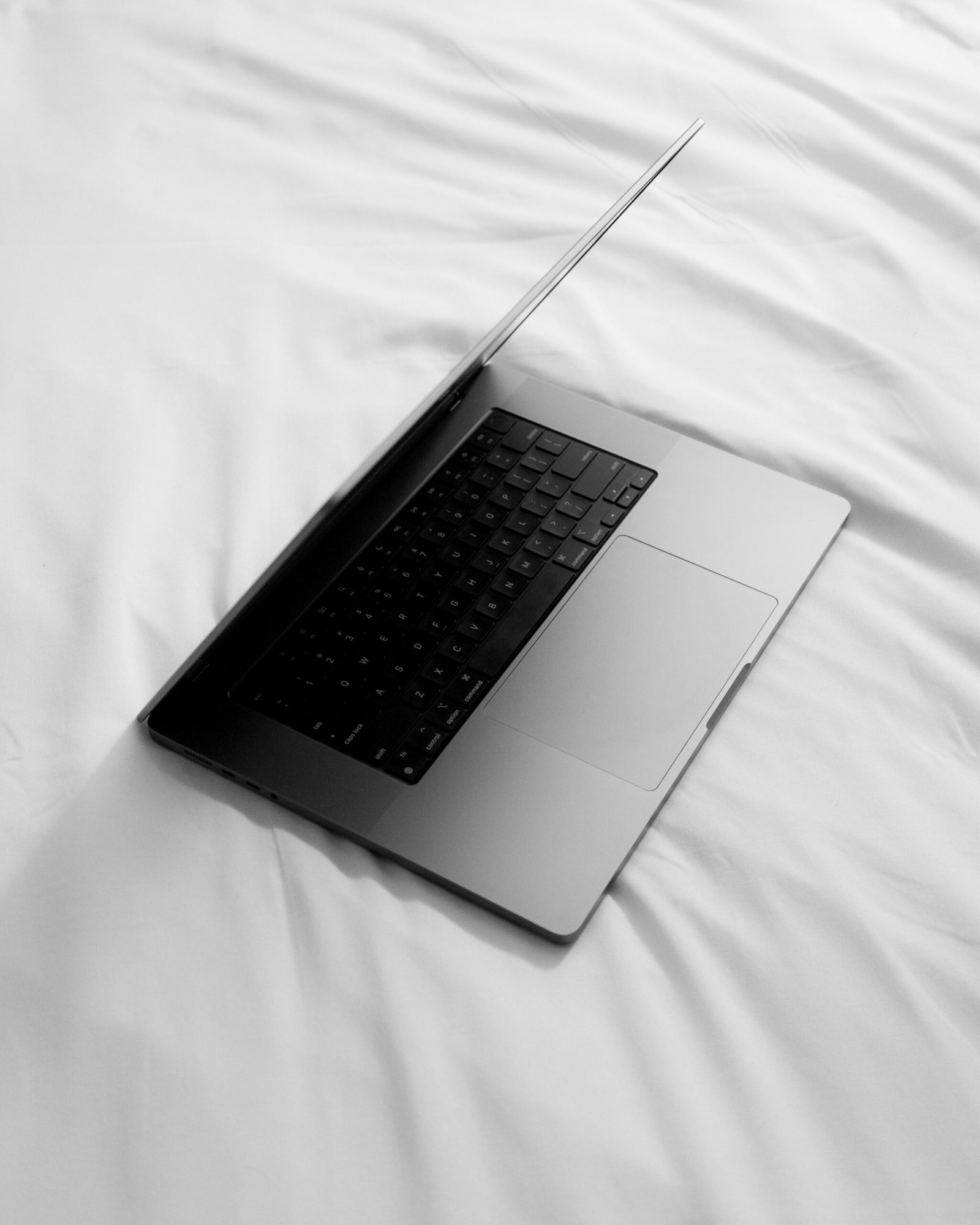 a black and white photo of a laptop on a bed